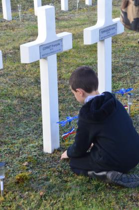 Un garçon plante un bleuet dans une nécropole